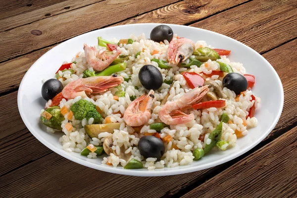 Rice porridge with shrimps and vegetables. On a wooden background