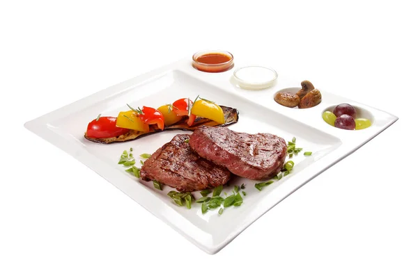 Pork steak with sauces and vegetables. On a white background Royalty Free Stock Photos