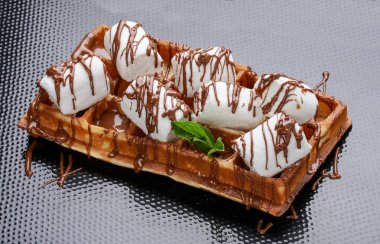 Karanlık bir arka planda Belçika tatlı waffle'ı. Marshmallow ve karamel şurubu ile doldurulmuş