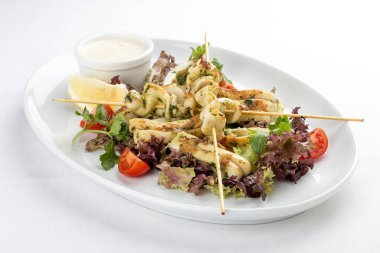 Şişlerde ızgarada salata ve soslu kalamar. Beyaz arka planda