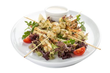 Şişlerde ızgarada salata ve soslu kalamar. Beyaz arka planda