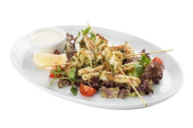 Şişlerde ızgarada salata ve soslu kalamar. Beyaz arka planda