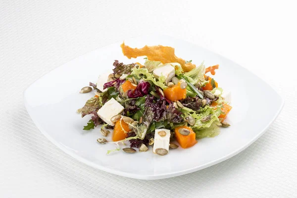 Salada com abóbora e feta em um fundo branco. Vegetariano — Fotografia de Stock