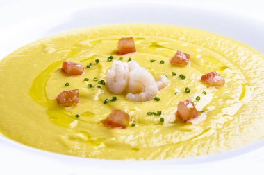 Beyaz zemin üzerinde karides olan balkabağı kremalı çorba.