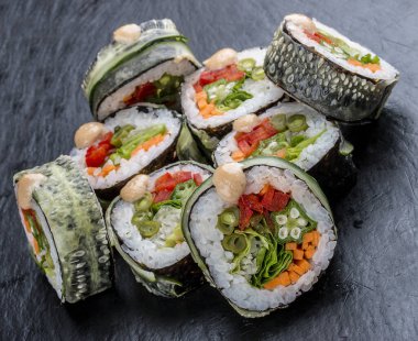 Siyah arka planda sebzeli suşi rulosu. Vejetaryen yemeği..