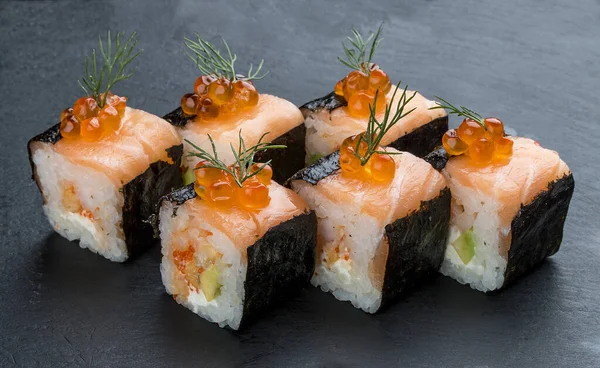 Rolo de sushi com salmão e caviar sobre fundo preto — Fotografia de Stock