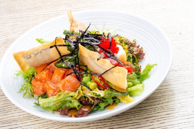 Krem peynirli somon salatası, kabak turşusu, daikon, fasulye, tobiko havyarı ve mango acı biber sosu. Pan-Asya yemeği.