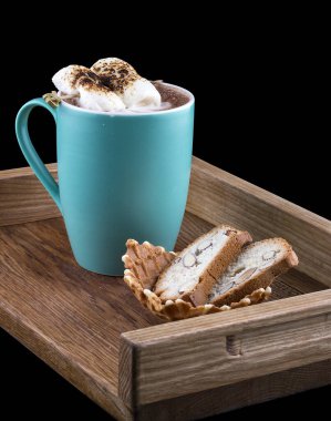 Tahta bir tahtanın üzerinde badem krakerli, koyu arkaplanda marşmelovlu kakao.