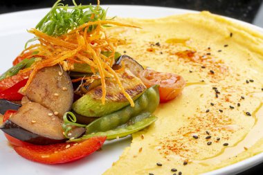 Fırında sebzeli humus. Siyah bir arka planda. Vejetaryen yemeği..