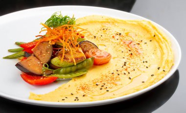 Fırında sebzeli humus. Siyah bir arka planda. Vejetaryen yemeği..