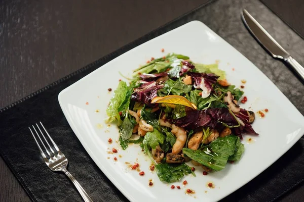 Masada bir plaka üzerinde karidesler ve yeşillikler ile salata