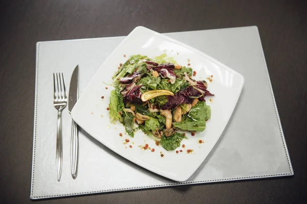 Masada bir plaka üzerinde karidesler ve yeşillikler ile salata