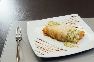 Masada beyaz bir tabak üzerinde beyaz sos ile kızarmış et