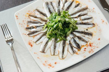 Masa üzerinde bir plaka üzerinde Yeşiller ile taze baharatlı Sprat