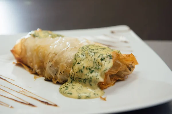 Fried meat with white sauce on a white plate on the table