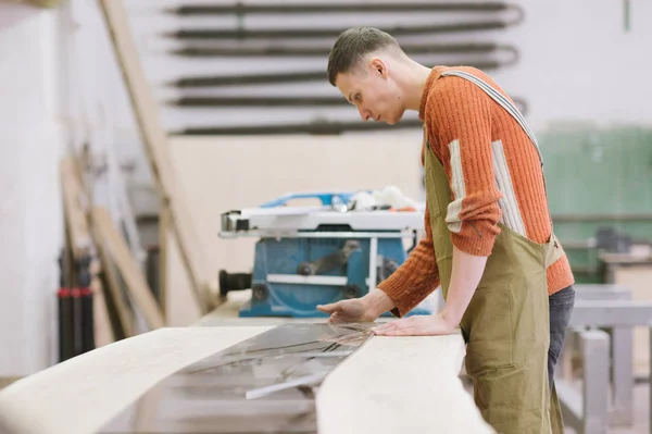 The master works on a surface grinding machine in the carpentry workshop