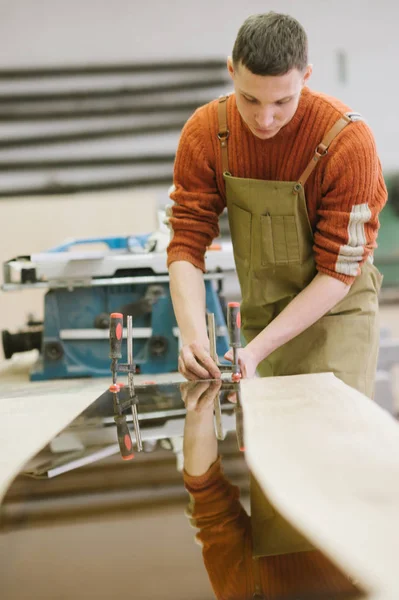 The master works on a surface grinding machine in the carpentry workshop