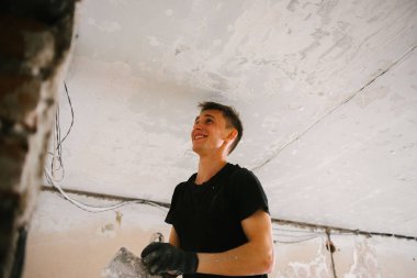 Bir adam bir spatula ile tavana eski boya kaldırır