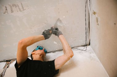 Bir adam bir spatula ile tavana eski boya kaldırır