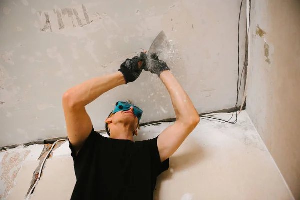 A man removes old paint from the ceiling with a spatula — Stock Photo, Image