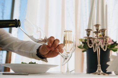 Adam bir şişeden bardağa şampanya döküyor.