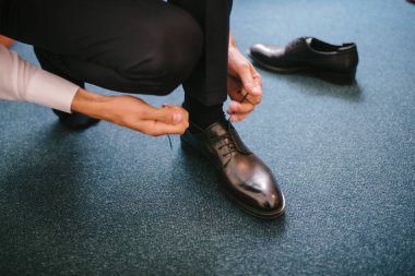 Takım elbiseli bir adam ayaklarına ayakkabı giyer..