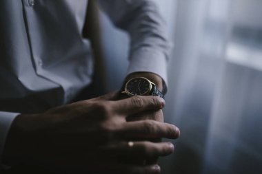 Takım elbiseli bir adam elindeki saati yakın alerler..