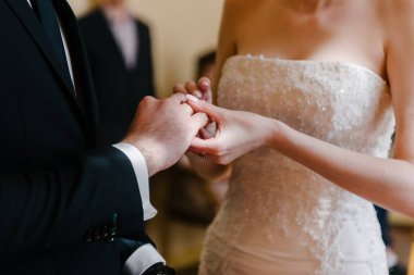 Damat geline yakın bir şekilde alyans takıyor. Gelin gelin gelinlik üzerine damat koyar.