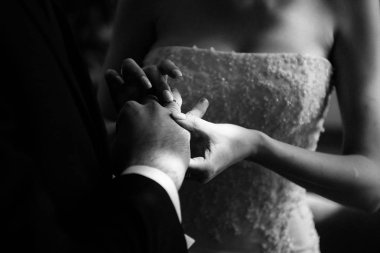 Damat geline yakın bir şekilde alyans takıyor. Gelin gelin gelinlik üzerine damat koyar.