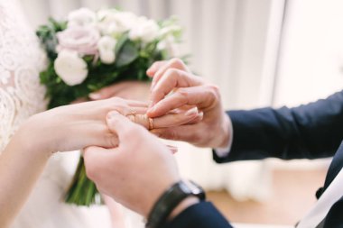 Damat geline yakın bir şekilde alyans takıyor. Gelin gelin gelinlik üzerine damat koyar.