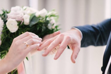 Damat geline yakın bir şekilde alyans takıyor. Gelin gelin gelinlik üzerine damat koyar.