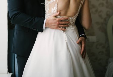 Takım elbiseli damat gelini gelinlikle kucaklıyor.