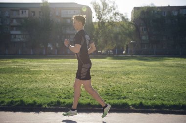 Atlet çim üzerinde kulaklık jogs