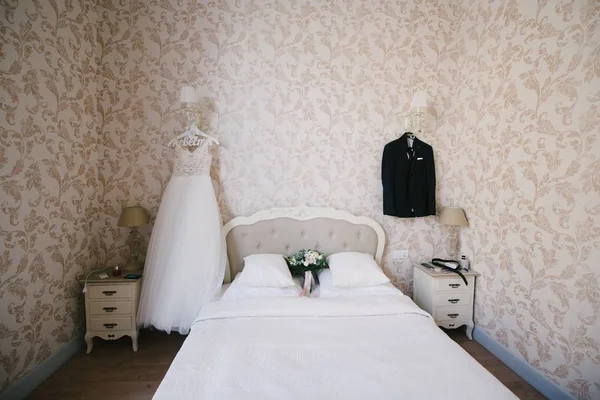 Suknia ślubna wisząca w domu w sypialni — Zdjęcie stockowe