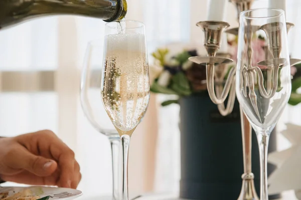 Man pours champagne into a glass from a bottle — Stock Photo, Image