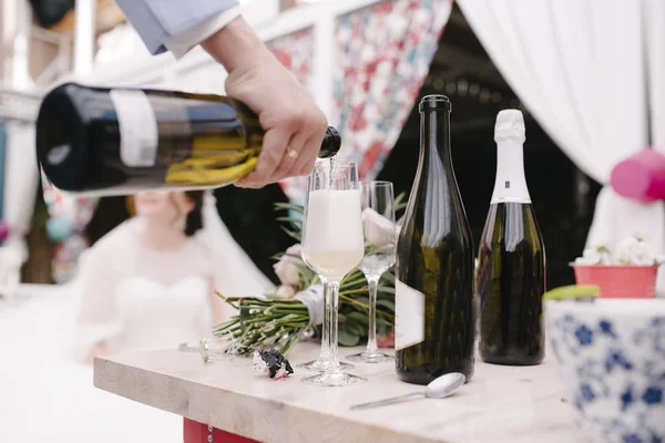 Man pours champagne into a glass from a bottle — Stock Photo, Image