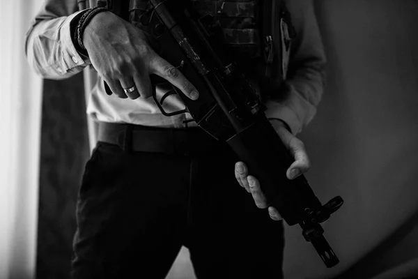Takım elbiseli ve vücut zırhı giymiş bir adam elinde makineli tüfek tutuyor.. — Stok fotoğraf