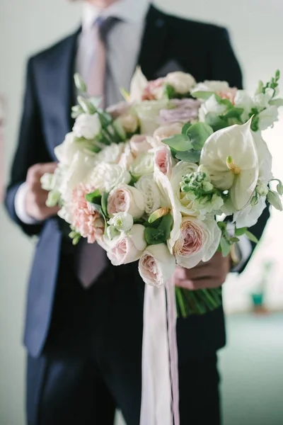 양복을 입은 남자가 꽃의 웨딩 꽃다발을 들고 있다.. — 스톡 사진
