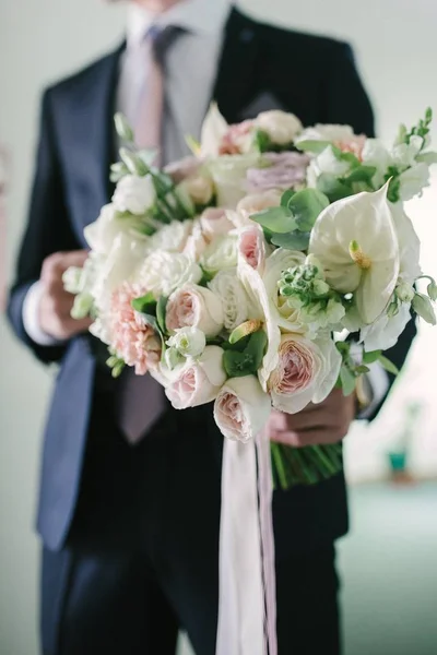 Un hombre con traje sostiene un ramo de flores de boda de cerca. . — Foto de Stock