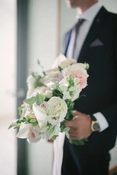 Un hombre con traje sostiene un ramo de flores de boda de cerca. . — Foto de Stock