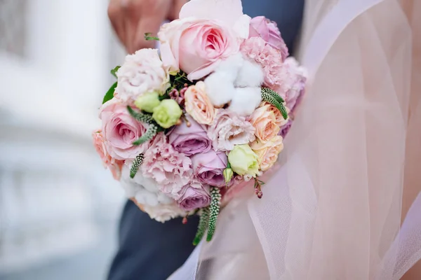 Un homme en costume tient un bouquet de fleurs de mariage en gros plan . — Photo