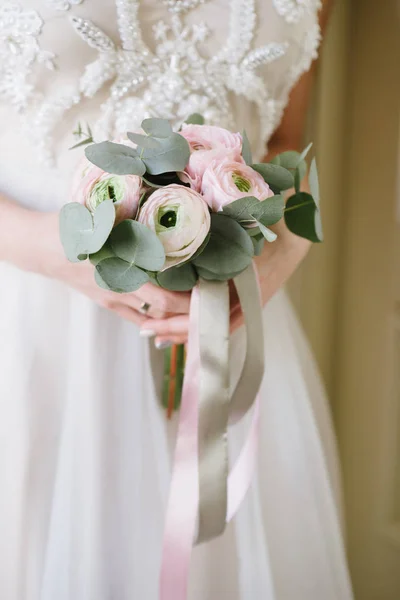 Mariée dans une robe de mariée tenant un bouquet de mariage dans ses mains gros plan — Photo