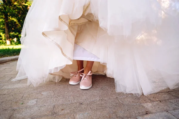 De benen van de bruid in een trouwjurk in schoenen — Stockfoto