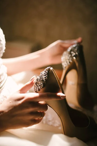 Mariée dans une robe de mariée blanche tenant des chaussures de mariage dans ses mains — Photo