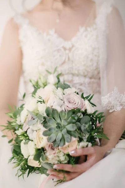 Mariée dans une robe de mariée tenant un bouquet de mariage dans ses mains gros plan — Photo