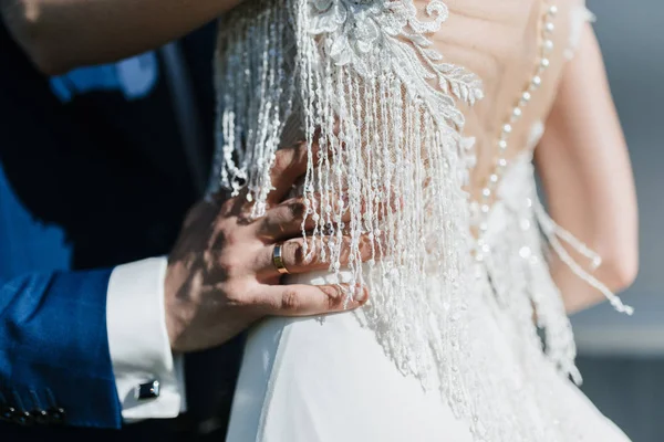 Le marié en costume étreint la mariée dans une robe de mariée — Photo