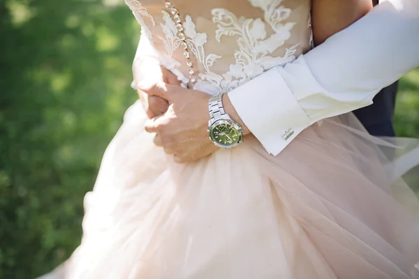 O noivo em um terno abraça a noiva em um vestido de casamento — Fotografia de Stock