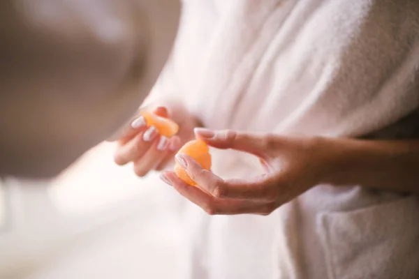 Mujer limpia la mandarina con las manos cerca — Foto de Stock