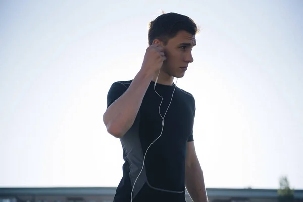 The athlete puts on headphones before jogging