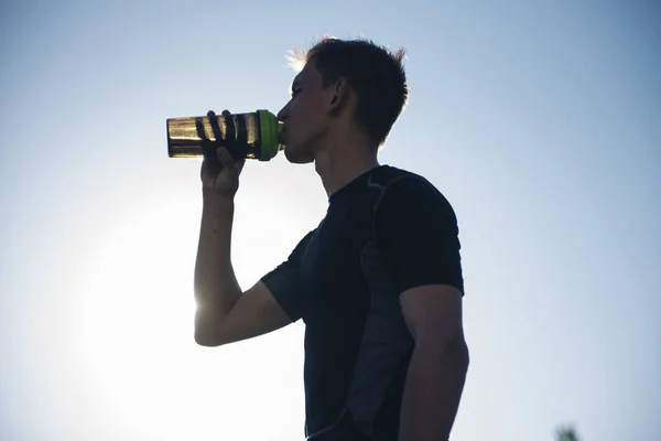 tired athlete man drinking water from a shaker